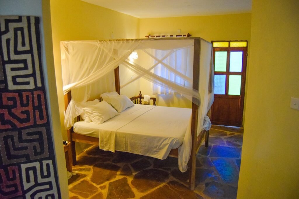 A four poster double bed in a yellow bedroom at Blue Marlin Beach Hotel