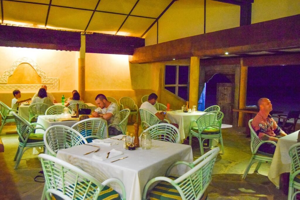 Blue Marlin Beach Hotel restaurant  with dimly lit yellow walls and pale green chairs