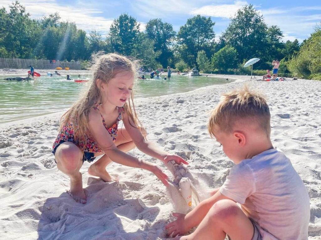 Siblings play in the sand at Castel Camping La Garangeoire lagoon