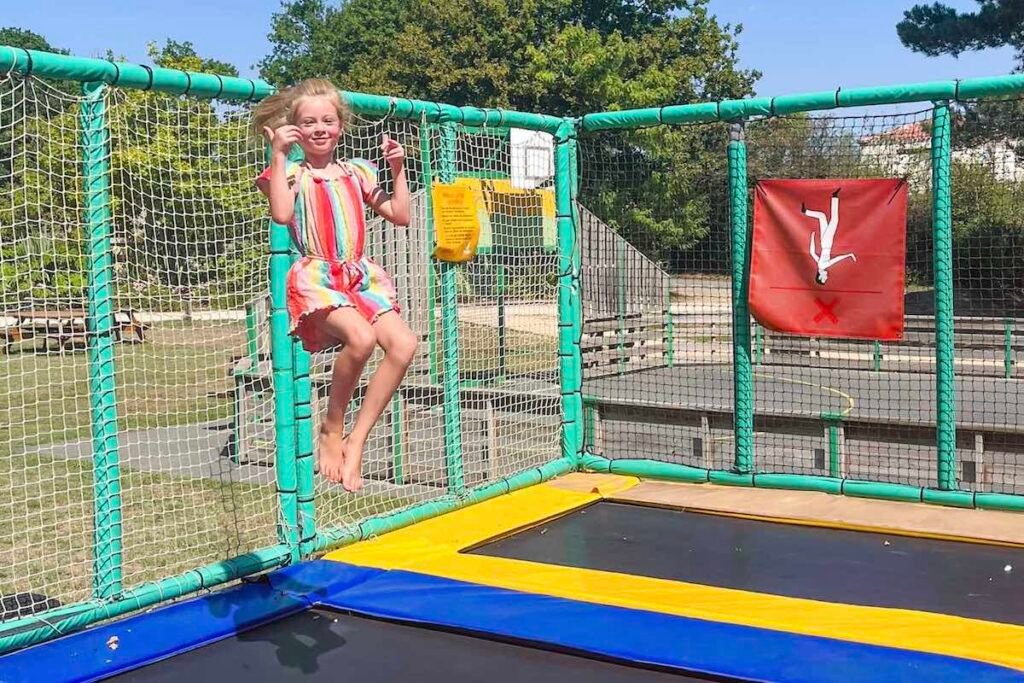 Girl plays on trampolines at Castel Camping La Garangeoire