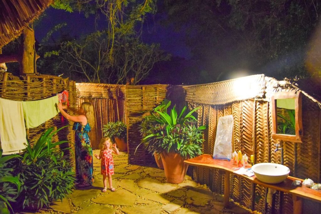 A mother and child hang clothes up in their outside bathroom at Distant Relatives Ecolodge & Backpackers