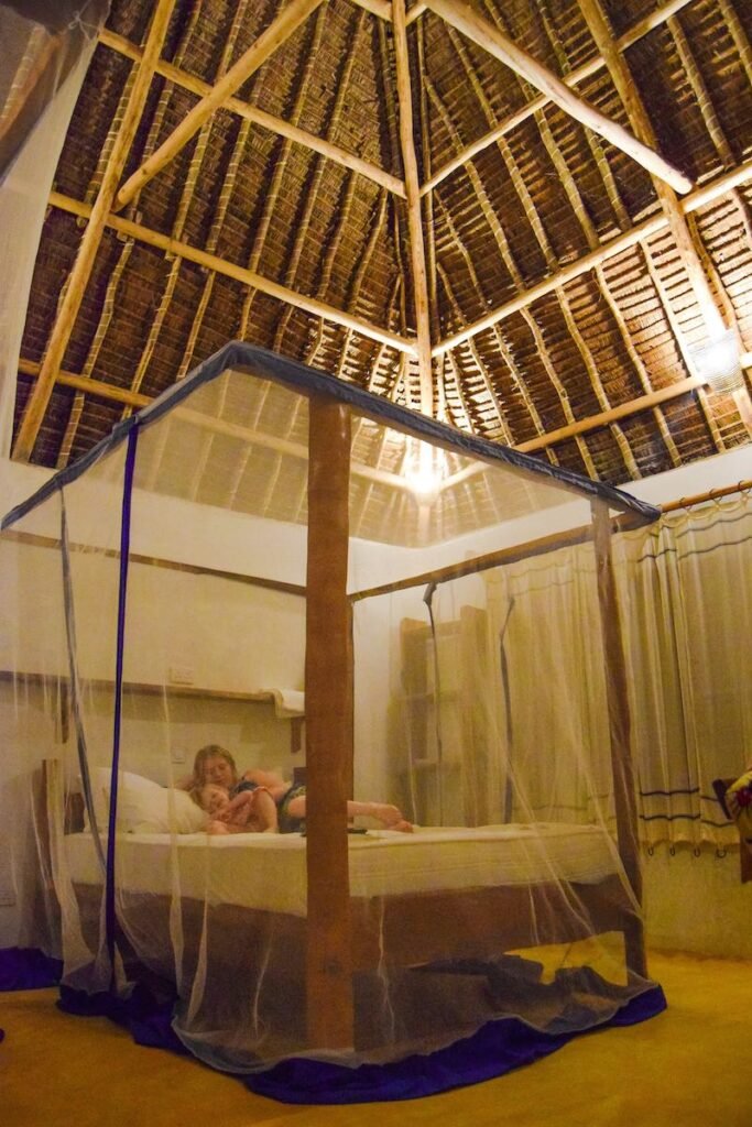 Mother and child relax on a double bed in their private wooden banda at Distant Relatives Ecolodge & Backpackers