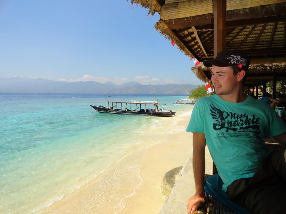 Man sits at a beach hut, looking out on to Gili Meno Beach