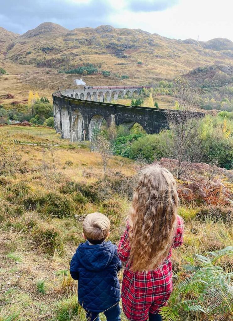 two children watch the train crossing the Glenfinnan Viaduct