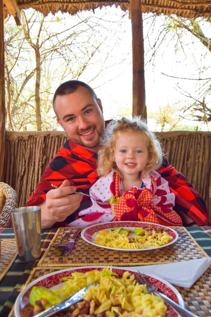 Father and daughter eat food at Maji Moto Maasai Cultural Camp