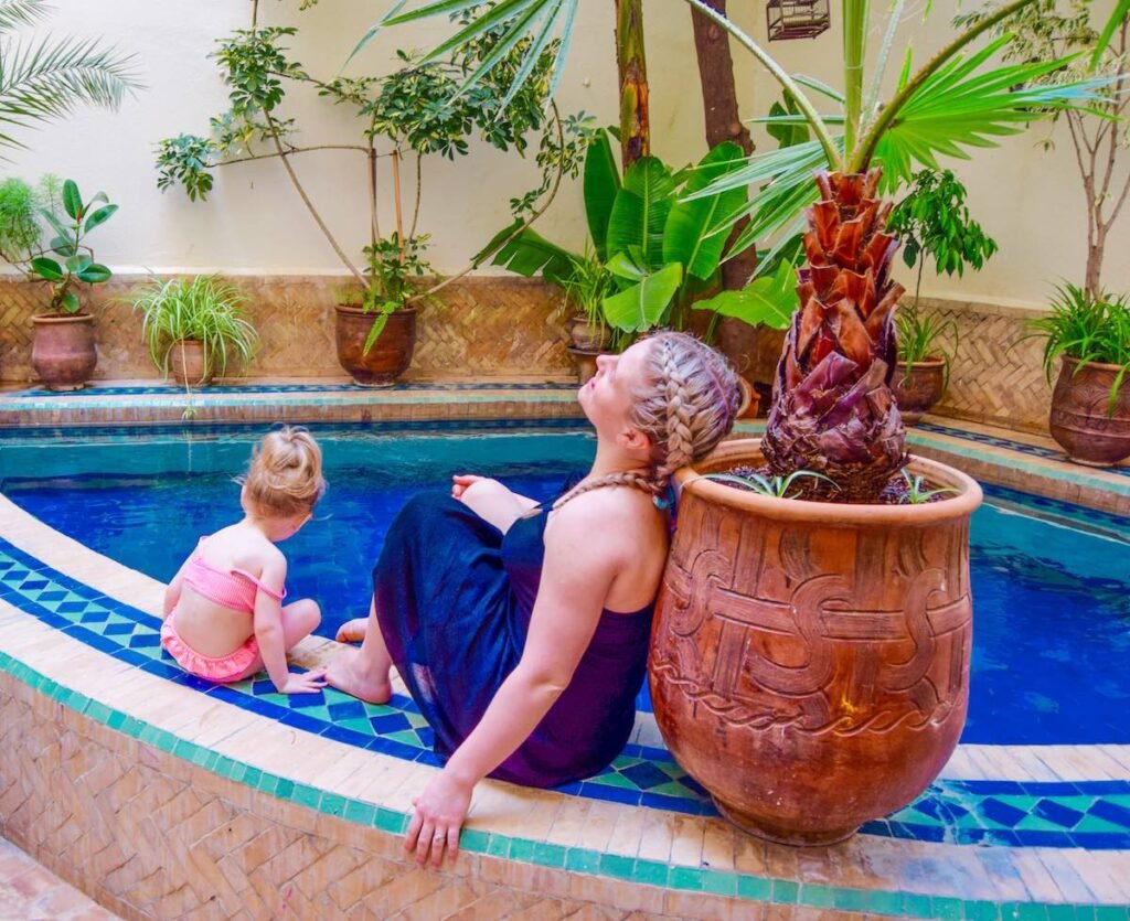 Mother and young daughter sit relaxing around the pool at Riad La Cle De Fes pool