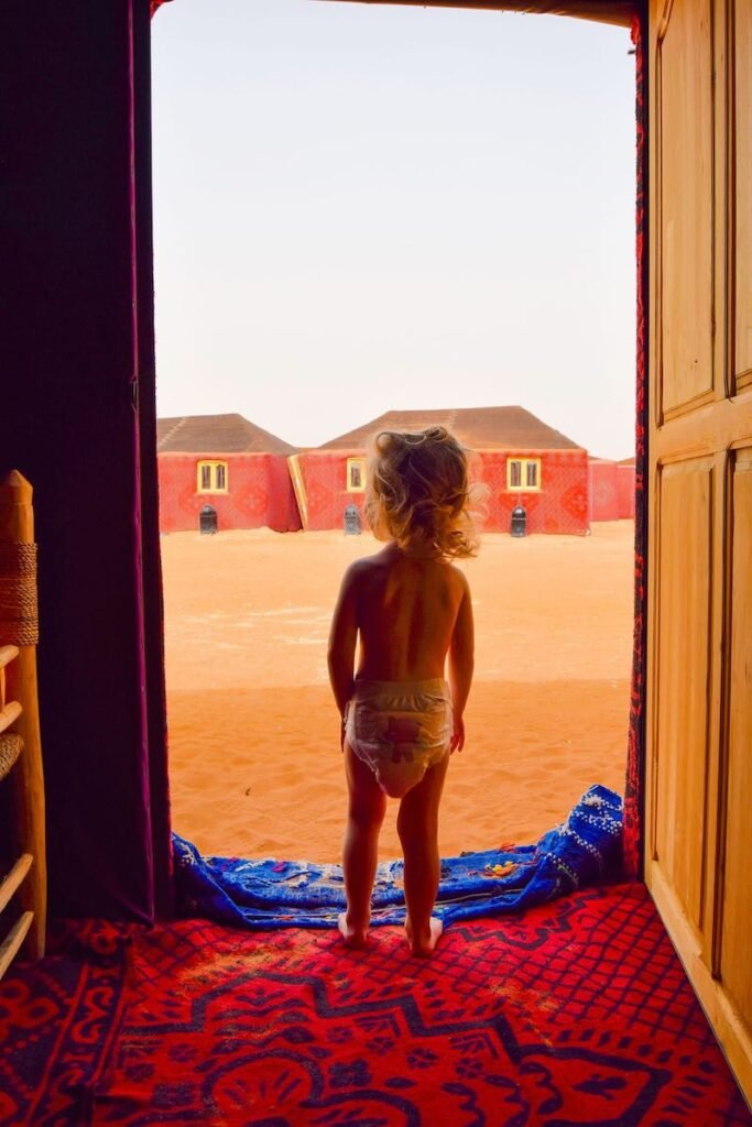 Young child looks out from her desert safari tent, at Ali and Sara’s Desert Palace